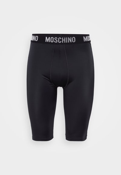 Shorts noirs extensibles avec une taille élastique arborant le logo Moschino en blanc. Texture lisse, design à mi-cuisses et coupe ajustée.
