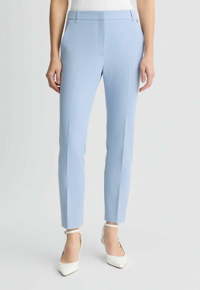 Pantaloni azzurri su misura con vestibilità slim, dotati di vita piatta, tasche laterali e una finitura in tessuto leggero e morbido.