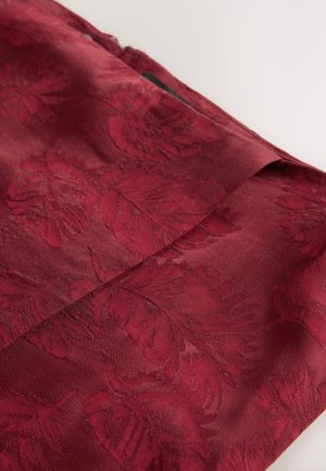 Weinroter Stoff mit floralem Muster, der eine glatte Textur und einen dezenten Glanz aufweist. Das Design beinhaltet eine Detailansicht einer umgeschlagenen Kante.