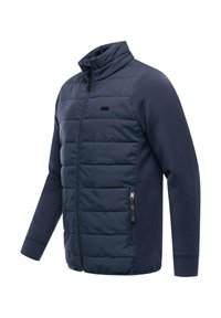 Laivastonsininen takki, jossa on toppattu etuosa ja verkkomainen hihansuu. Varustettu korkealla kauluksella, sivuvetoketjutaskuilla ja hillityllä logokoristeella.