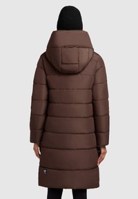 Pruun puffertagi horisontaalsete quiltitud mustritega, kapuutsiga ja keskmise pikkusega. Omab külgtaskut, millel on logo aksent allääres.