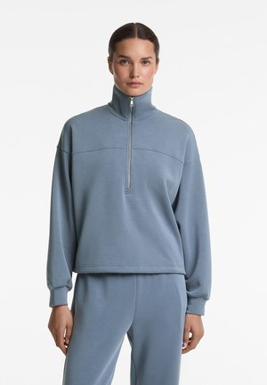 Hellblaues Reißverschluss-Sweatshirt mit hohem Kragen, langen Ärmeln, gerippten Bündchen und einem cropped Saum, aus weichem, strukturiertem Stoff.