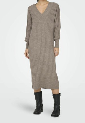 Taupe V-hals, lange mouw, geribbelde gebreide jurk tot halverwege de kuit. Gestyled met zwarte enkellaarsjes met gespen. Zachte textuur.