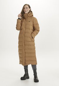 Lang brun pufferjakke med høj krave, trykknaplukninger og sidelommer. Stoffet er glat; har et diskret logo og en tætsiddende silhuet.