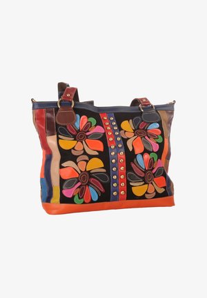 Colorful leather tote bag with flower patterns, brass studs, double handles, and multicolored patchwork details on a black background.