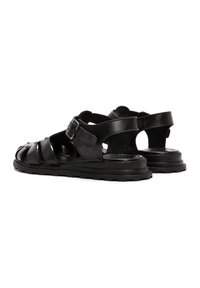 Sandali in pelle nera con design a fasce incrociate, fibbia regolabile, suola piatta e finitura testurizzata, dotati di ritagli per la traspirabilità.