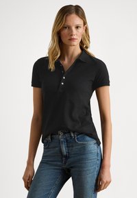 Svart poloshirt med krage, treknapps åpning og korte ermer; kombinert med blå denimjeans. Jevn tekstur.