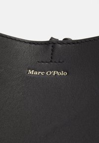 Czarne skórzane buty o gładkiej teksturze i minimalistycznym designie. Posiadają złote, wytłoczone logo "Marc O'Polo" oraz staranne przeszycie wzdłuż krawędzi.