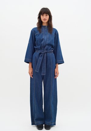Denim-Overall mit weitem Bein, langen Ärmeln und einem taillierten Bund. Verfügt über kontrastierende Nähte und einen hohen Kragen für zusätzliche Details.