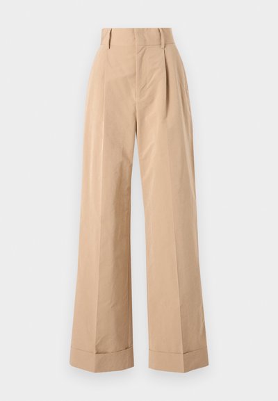 Beige weit geschnittene Hose mit hoher Taille, mit Falten und glatter Textur. Die Säume sind umgeschlagen, was eine strukturierte Note hinzufügt.