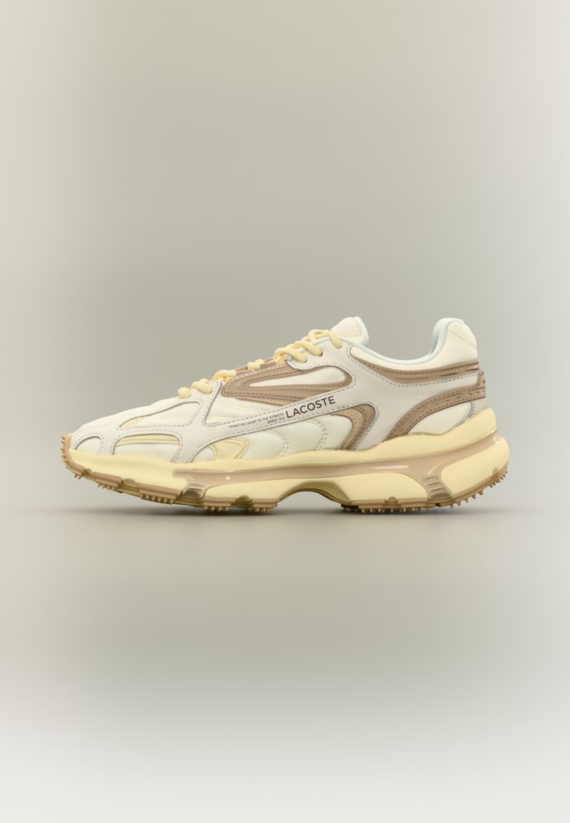 Lacoste'i tossud, millel on kreemitooni pealisosa, beežid lisad, tekstureeritud ülekatted ja paks, paindlik tald, millel on haardetehnoloogia.