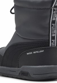 Bota negra de Puma resistente al agua con suela texturizada y raya vertical de la marca en el lateral.