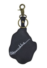 Zwart lederen sleutelhanger in een onregelmatige vorm met een gestructureerd oppervlak, voorzien van een messing clip en ring, en een witte handtekeningdetail.