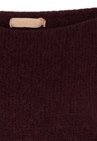 Burgundy stickad tröja med en texturerad yta. Har en etikett med namnet "MARTA" i guldskrift och en enkel rund halsringning.
