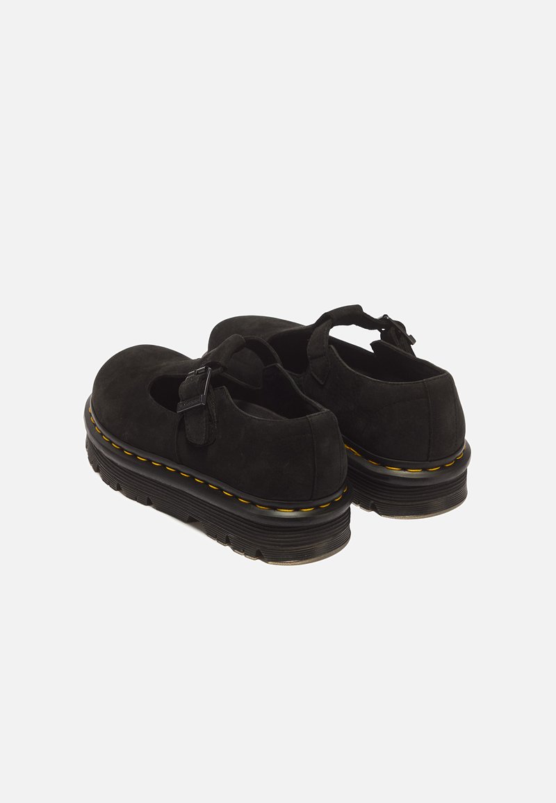 Black Mary Jane shoes with thick ridged soles and yellow stitching, featuring a buckle strap over the top.