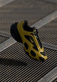 Schwarzer und gelber Sportschuh mit einem Obermaterial aus Mesh, geschwungenem Design, auffälligem Nike-Logo und strukturiertem Profil.