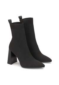 Black sock-style ankle boots with a pointed toe, ribbed upper, and a chunky black heel. Made of soft, stretch fabric for comfort.