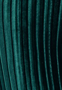Tessuto in velluto di un profondo verde mare con strette striature verticali. La textura è morbida e soffice, mostrando una lucentezza uniforme sulla superficie.