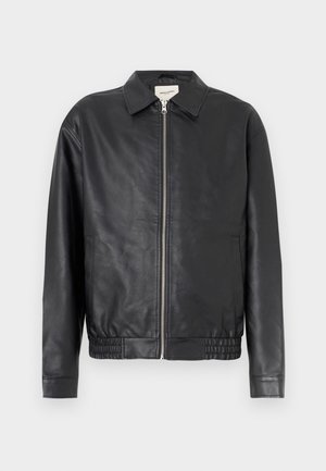 Musta nahkatakki vetoketjulla, terävä kaulus, joustava vyötärönauha ja sivutaskut; sileä pinta, vähän saumoja.