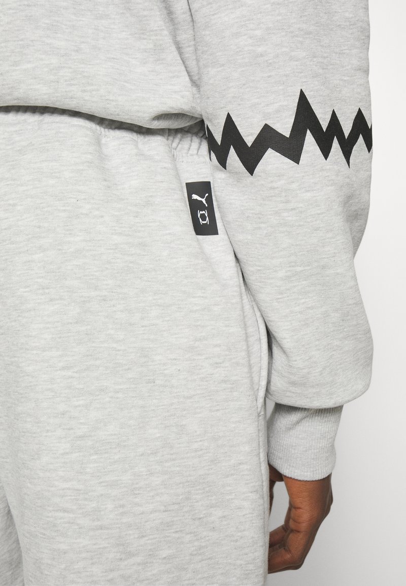 Felpa grigia con un motivo a zigzag nero sulla manica, e un piccolo logo nero sulla vita. Tessuto morbido e vestibilità comoda.