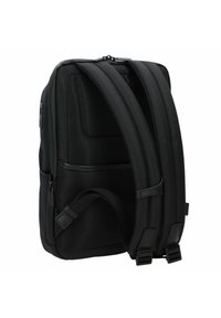 Zaino nero con esterno in rete testurizzata, spallacci imbottiti e regolabili, compartimenti con zip e dettagli lisci. Forma rettangolare.