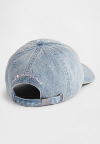 Lyseblå baseballcaps i denim med justerbar stropp, med brodert rosa tekst på baksiden. Myk tekstur og strukturert form.