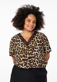Blouse à manches courtes en imprimé léopard avec un décolleté en V et des garnitures en dentelle noire. Présente une coupe ample et une texture de tissu douce.