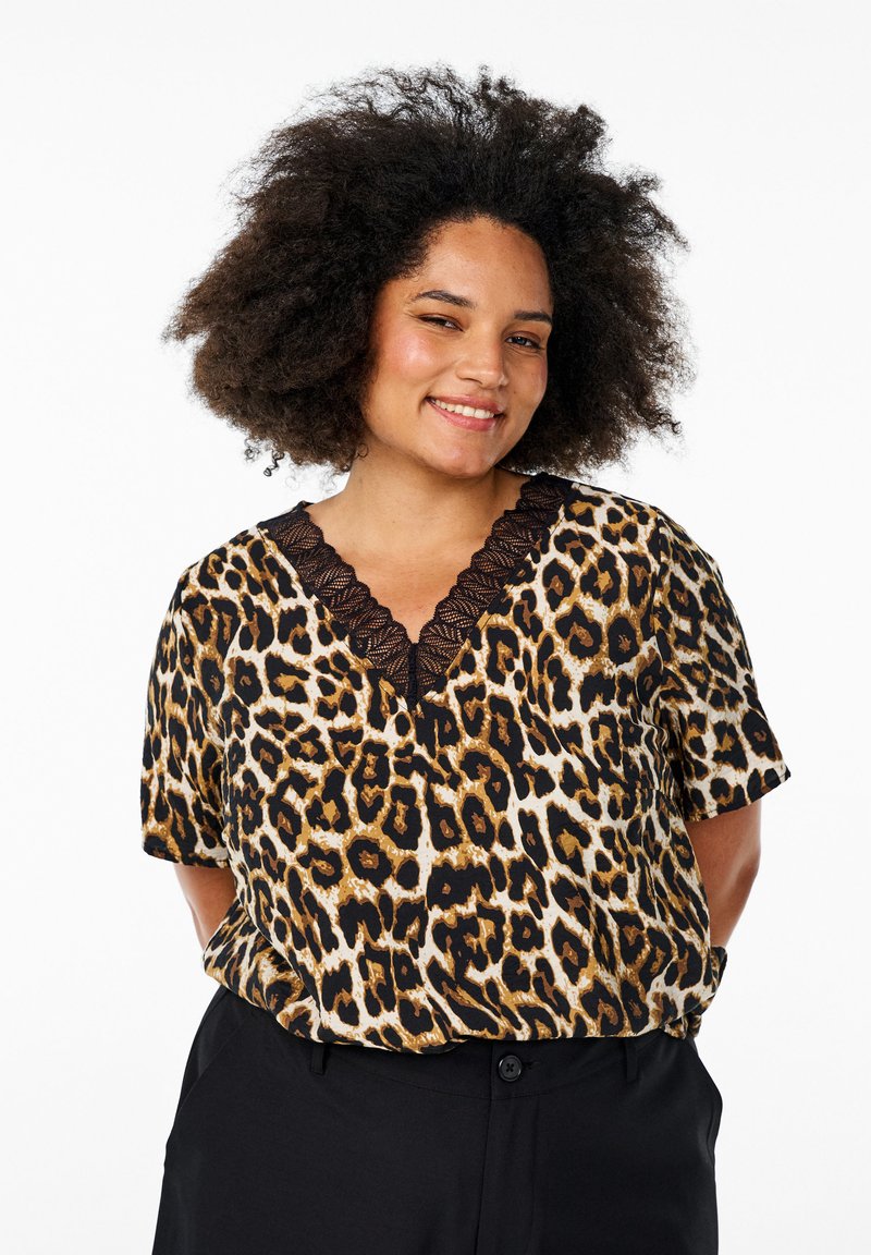 Blouse à manches courtes en imprimé léopard avec un décolleté en V et des garnitures en dentelle noire. Présente une coupe ample et une texture de tissu douce.