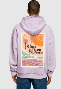 Lila kapucnis pulóver, amely pálmafák, hullámok és nap grafikai nyomtatásával rendelkezik, felirattal: "SURF CLUB CALIFORNIA." Puha, texturált anyag.