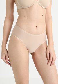 Beige naadloze ondergoed met een gladde textuur. Kenmerkt zich door een medium hoge taille en een elastische tailleband voor comfort. Geen zichtbare naden of patronen.