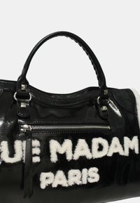 Svart lackläderhandväska med vit texturerad tryck som säger "BLUE MADAM PARIS." Innehåller en blixtlåsficka och stadiga handtag.