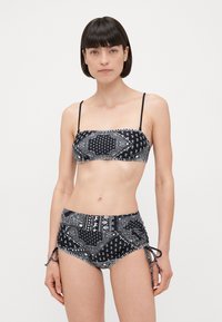Černobílý bikini s bandeau topem a vzorovaným designem a vysokým pasem s nastaviteľnými vázáním na bocích.