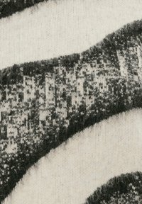 Nahaufnahme von weichem Wollstoff mit schwarz-weißen abstrakten Mustern und flauschiger Textur.