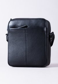 Black leather messenger bag with a textured finish, square shape, top handle, and adjustable strap. Features a front pocket.