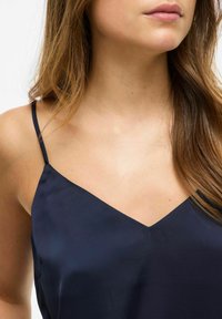 Granatowa satynowa koszulka na ramiączkach z cienkimi regulowanymi ramiączkami, z głębokim dekoltem w kształcie V i gładką teksturą.
