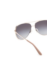 Ochelari de soare cu ramă din metal auriu și lentile gri în degradé. Caracteristici: design ușor, bară curbă pe sprânceană și vârfuri din plastic maro pentru brațe.