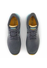 Graue Sportschuhe mit einem atmungsaktiven Strickobermaterial, Sohle aus Fresh Foam, türkisfarbenen Akzenten und einer gelben Innensohle, die ein Schnürdesign aufweisen.