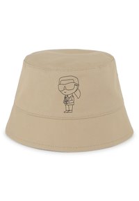 Chapeau seau beige en toile avec une texture lisse. Présente un graphique au contour noir d'un personnage portant des lunettes de soleil à l'avant.