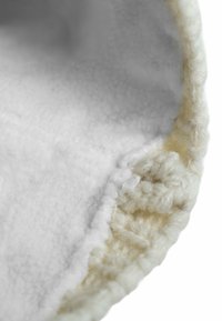 White plush slipper interior with a soft, fuzzy texture and a knitted beige rim. Seam details are visible along the edge.