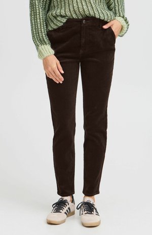 Bruine corduroybroek met een slim fit, voorzien van zijzakken en een knoopsluiting. Gecombineerd met lichte sneakers en een gebreide groene trui.