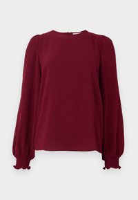 Burgunderfarget langermet bluse med rund hals, teksturert stoff, elastiske mansjetter og en liten lukking bak. Uformell design.
