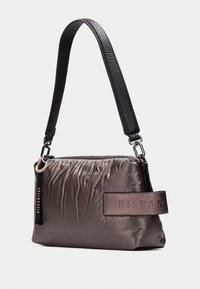 Sac en duvet léger couleur taupe avec une texture froissée, des accents en cuir et une bandoulière noire. Présente un détail de logo doré sur le côté.