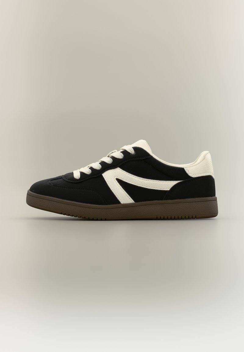 Czarno-biały sneaker o fakturze przypominającej zamsz, z niskim profilem, płaskimi sznurowadłami i gumową podeszwą z wzorzystym bieżnikiem.