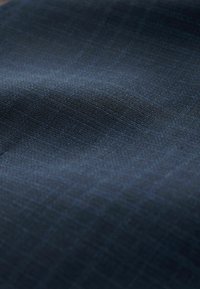 Marineblåt stof med et subtilt ternet mønster, der har en glat tekstur og en let glans, primært lavet af vævede fibre.