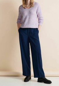 Light purple, textured knit sweater with a V-neck. Paired with navy wide-leg trousers and black chunky ankle boots. Simple design, no patterns.