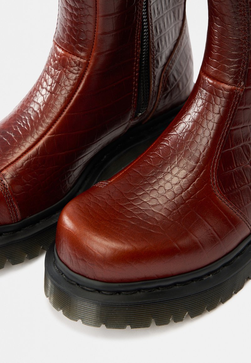 Red leather ankle boots with a textured crocodile pattern, featuring a black rubber sole and side zipper for easy wear.