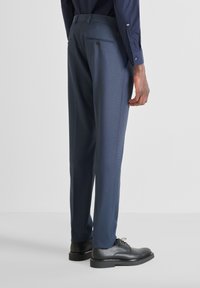 Pantaloni da abito navy con finitura testurizzata, taglio dritto e due tasche posteriori, abbinati a scarpe da abito nere.