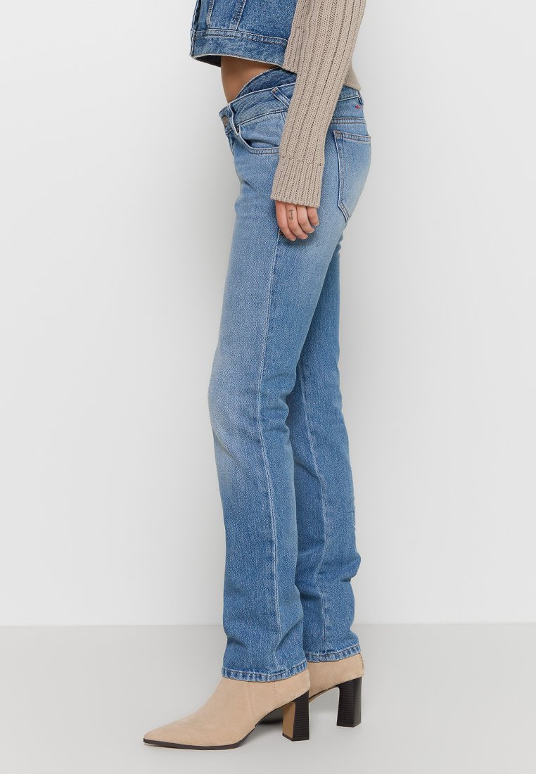Jeans in denim azzurro chiaro con una vestibilità slim, caratterizzati da una vita media e leggere sfumature. Abbinati a stivaletti beige con punta a stiletto.