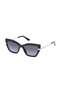 Gafas de sol negras de forma de ojo de gato con un marco superior estampado, lentes oscuros en degradado y acentos de metal dorado en las patillas. Acabado liso y brillante.