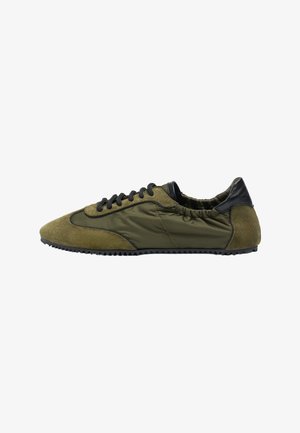 Olivgrüner Sneaker mit schwarzen Schnürsenkeln, Wildleder- und Nylonpaneelen, schwarzer Lederferse und strukturierter schwarzer Gummisohle.